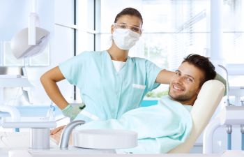 A female dentist and a man patient sitting in a dental chair.