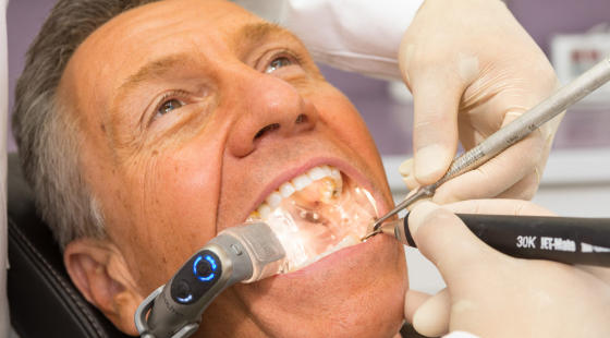 A man in a dental chair undergoing dental procedure.