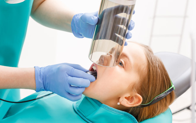 A young girl is getting her teeth cleaned by a dentist.