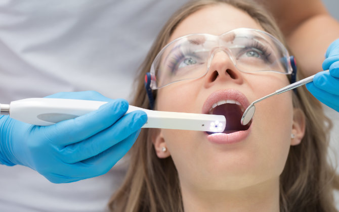 A woman is getting her teeth cleaned by a dentist.