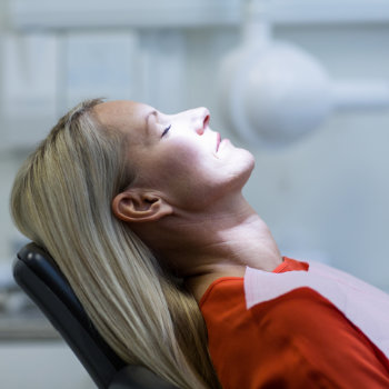 Relaxed woman under dental sedation sitting in a dental chair
