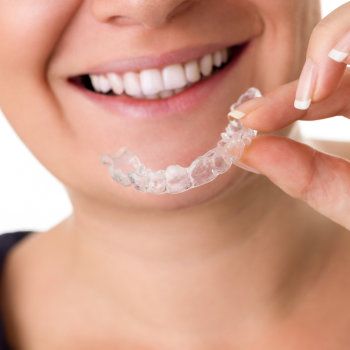 Woman with perfect teeth holding invisalign