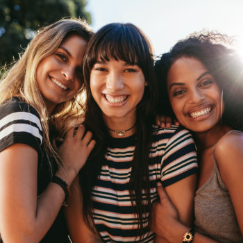 attractive female friends embrace and smile