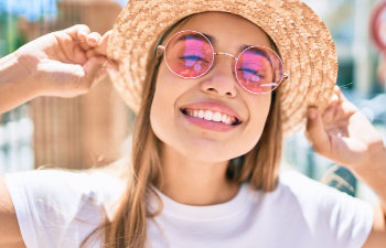 smiling girl in pink glasses and hat