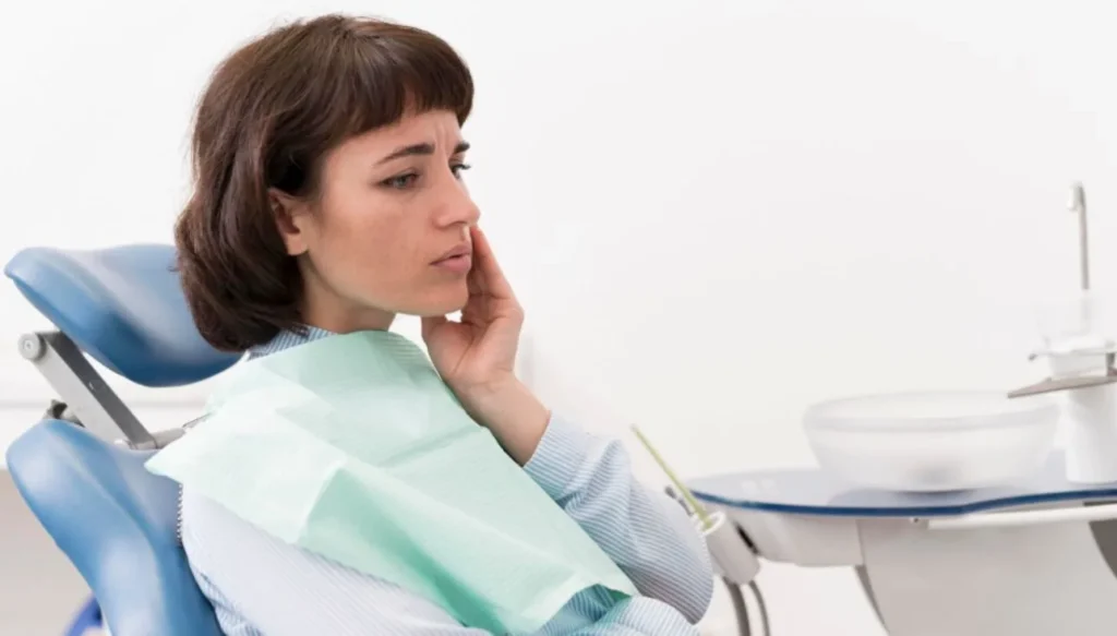 Woman holding her cheek during a dental appointment