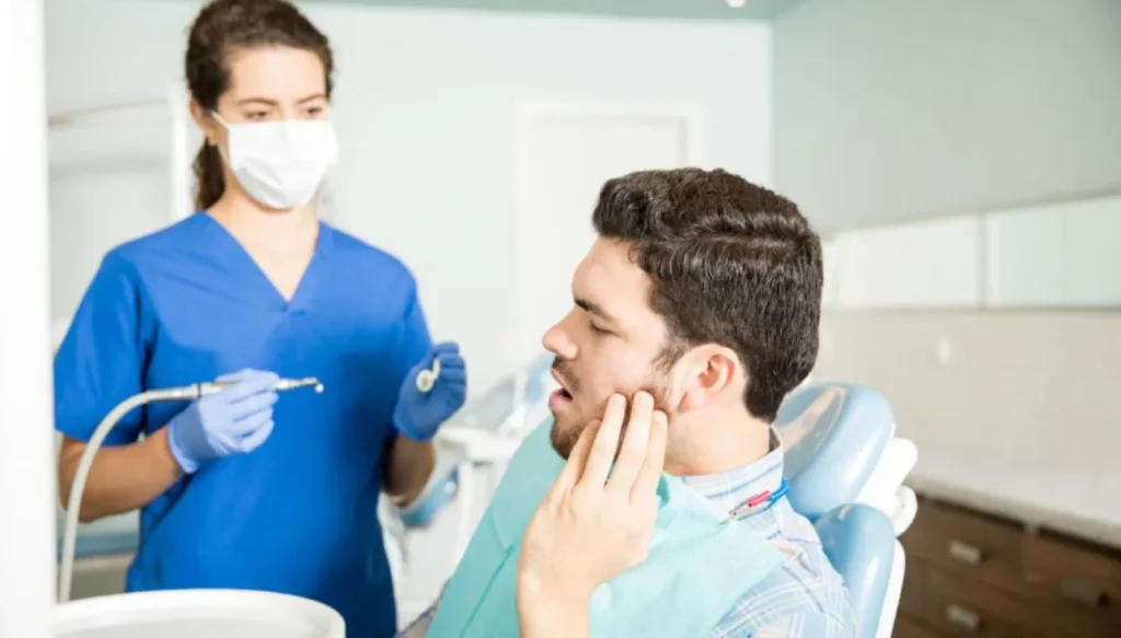 Man holding his cheek during a painful dental treatment